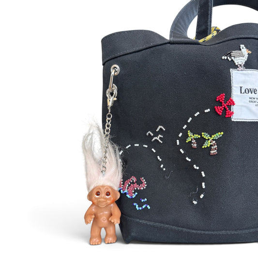 212vtg vintage troll doll keychain with fluffy white hair attached to a black canvas tote bag with beaded embroidery