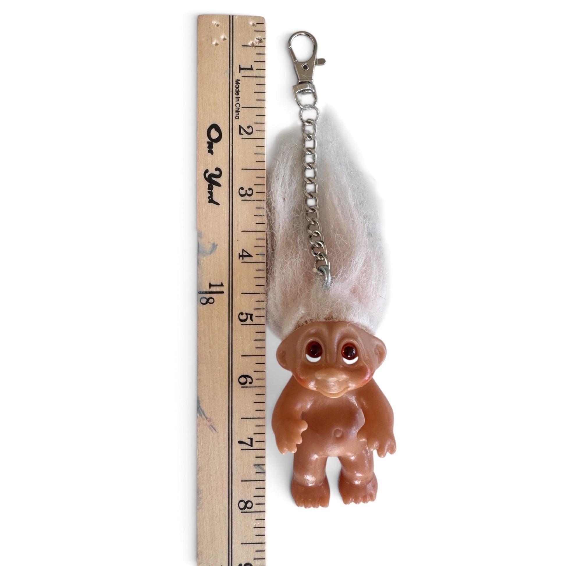 212vtg vintage troll doll keychain with fluffy white hair and brown vinyl body next to a wooden ruler for scale