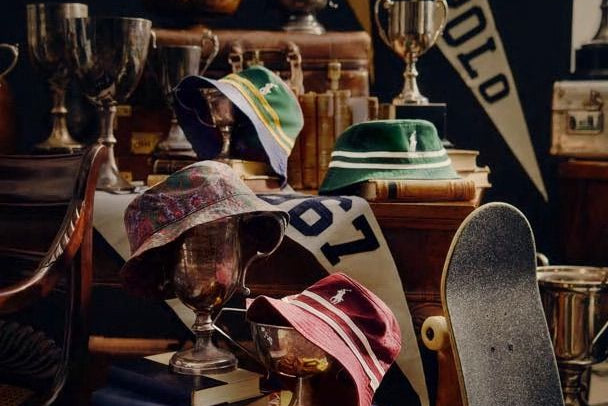 Vintage sports trophies, hats, and a skateboard on a table with a dark background
